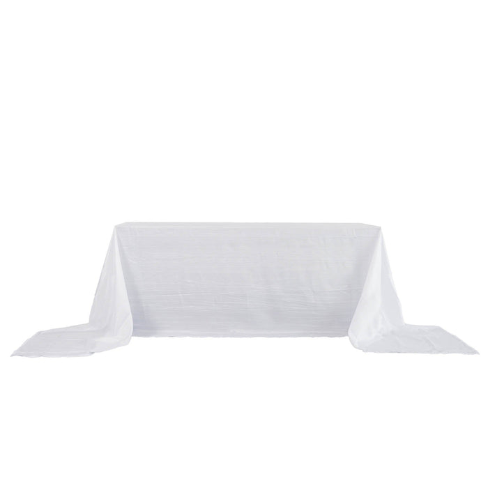 White tablecloth with elegant draping on a plain backdrop