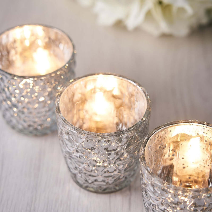 Set of three decorative glass candle holders with warm glowing candles.