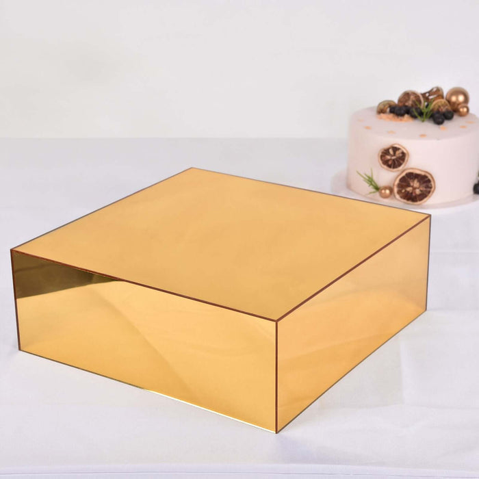 Gold rectangular box on a white table with a cake in the background.