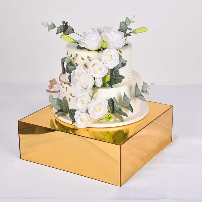 Elegant three-tier cake adorned with white roses and greenery on a gold base.