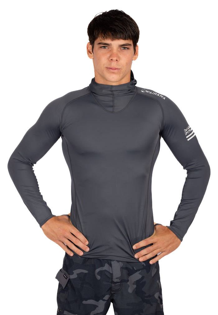 Male model wearing the Waihana Anthracite Carvico Hooded Surf Rashguard in charcoal gray with long sleeves, high neck hood, and Hawaiian flag logo on the sleeve, shown against a white background.