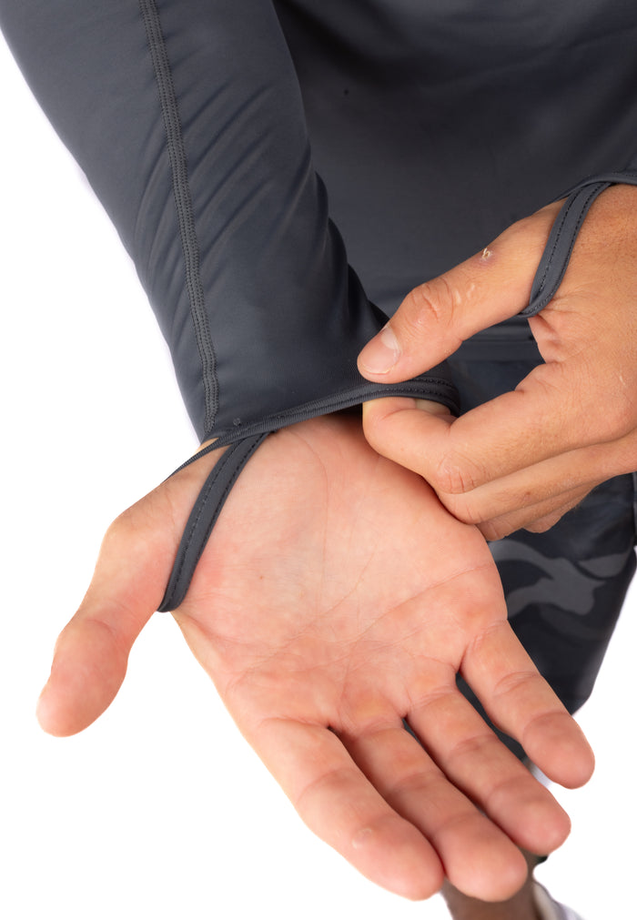 Close-up of a person adjusting the elastic wrist cuff of the Waihana Anthracite Carvico Hooded Surf Rashguard, highlighting the flatlock stitching and snug fit.
