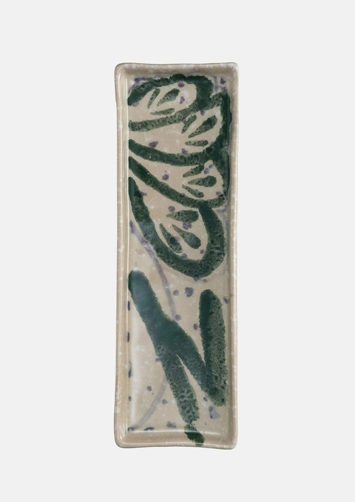 Long rectangular ceramic tray with multicolor paint splatter pattern.