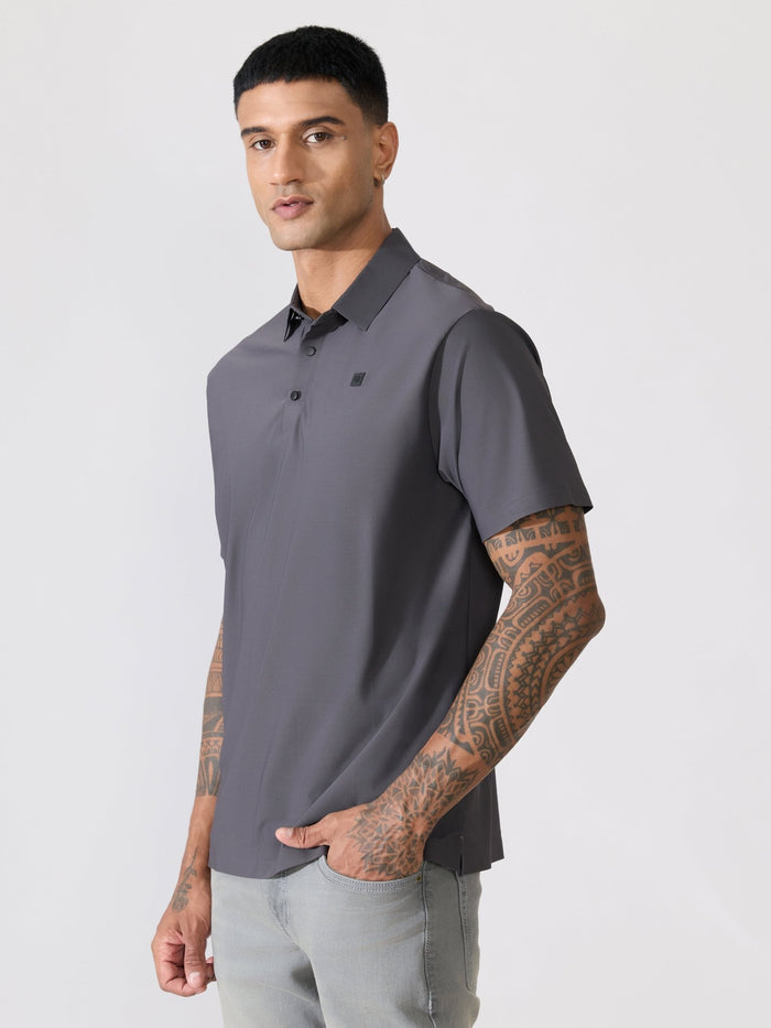 Man wearing a gray polo shirt with a black collar on a light gray background