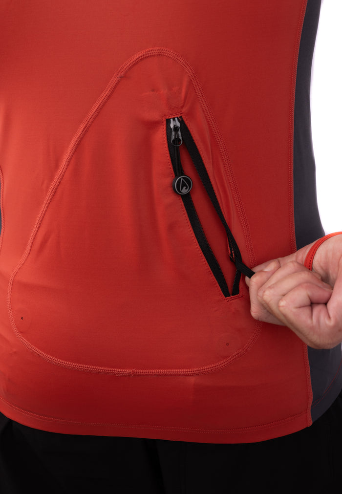 Close-up of the zippered chest pocket on the Waihana Canyon Hooded Voyager Rashguard in red and dark grey, with a hand pulling open the branded zipper.