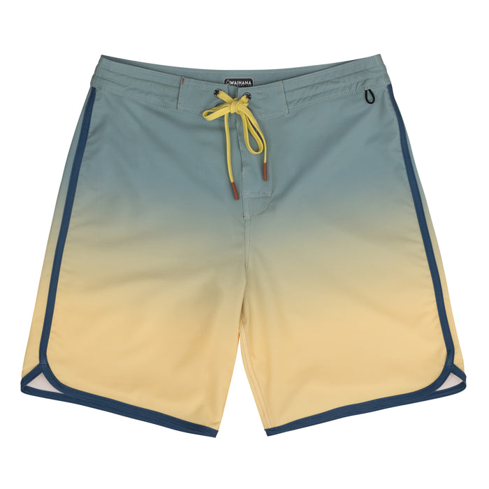 Waihana Dawn Patrol W1 board shorts laid flat, showing a teal-to-yellow ombre gradient with navy piping trim and a yellow drawstring tie.