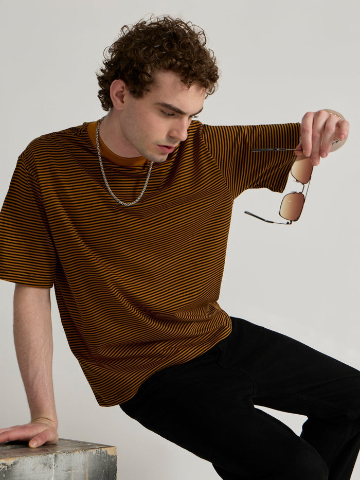 Man wearing a mustard yellow and black striped crew t-shirt