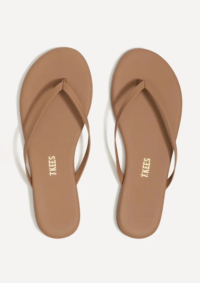 A pair of leather skinny strap TKEES sandals in nude.