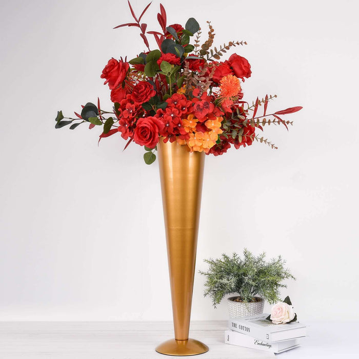 Gold cone vase with vibrant red and orange floral arrangement