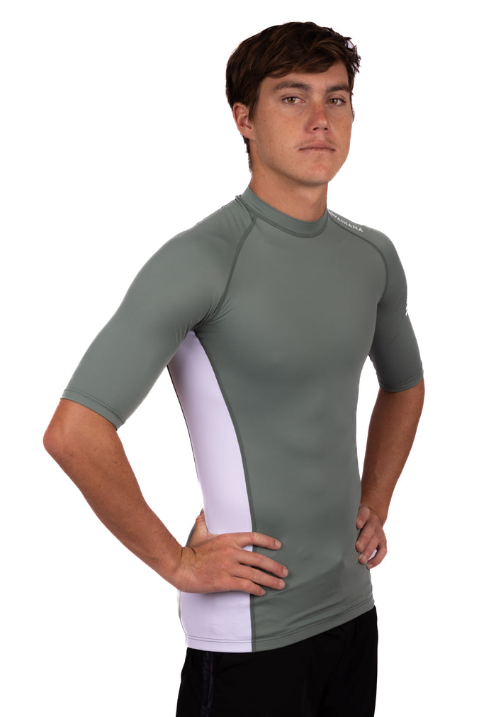 Male model wearing a Waihana olive green short sleeve rashguard with white side panel accents, shown from a three-quarter angle against a white background.