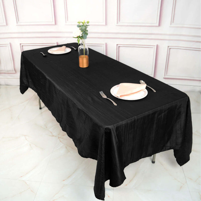 Elegant black tablecloth draped over a dining table set for two.