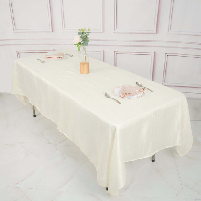 Elegant cream tablecloth set for dining with utensils and floral centerpiece.