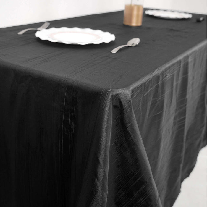 Black tablecloth draping a table set for dining with plates and cutlery.