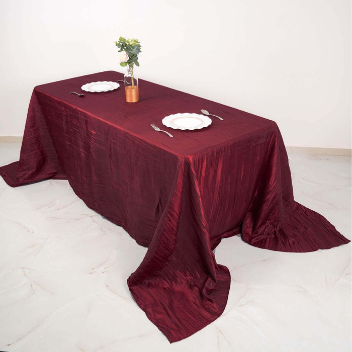 Burgundy tablecloth draped elegantly over a dining table with plates and a vase.