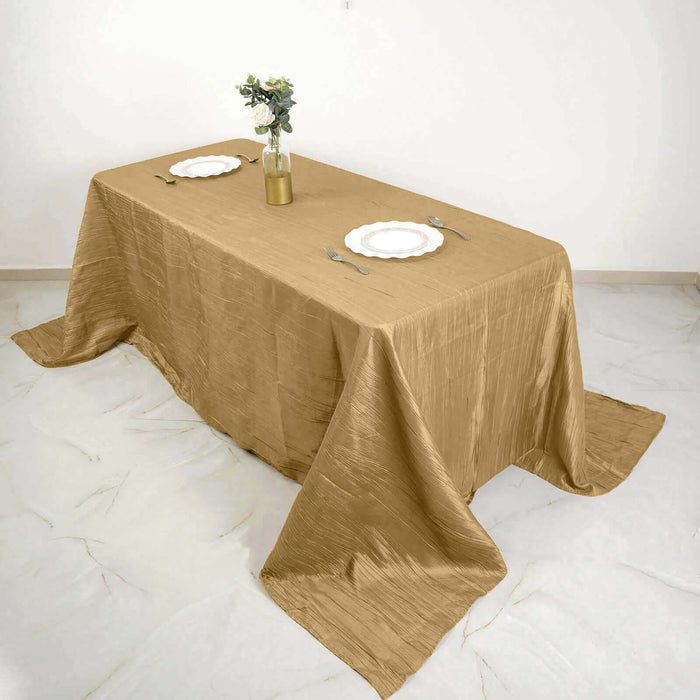 Elegant gold tablecloth draped over a dining table with plates and a vase.