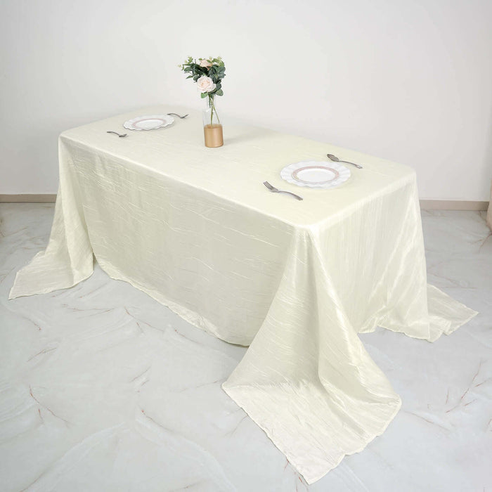 Elegant cream tablecloth set with plates and utensils on a minimalist table.