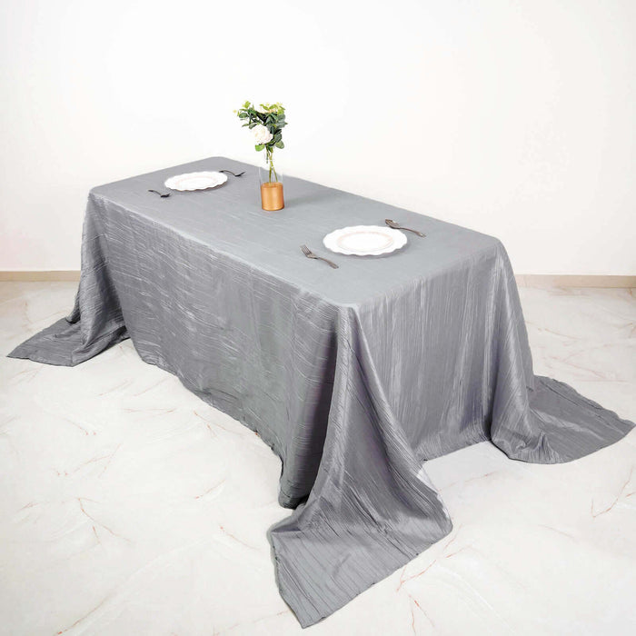 Gray tablecloth draped over a table with plates and a vase of flowers.