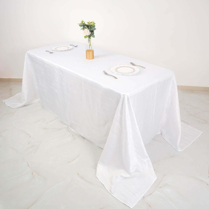 White table with elegant place settings and a flower vase centerpiece.