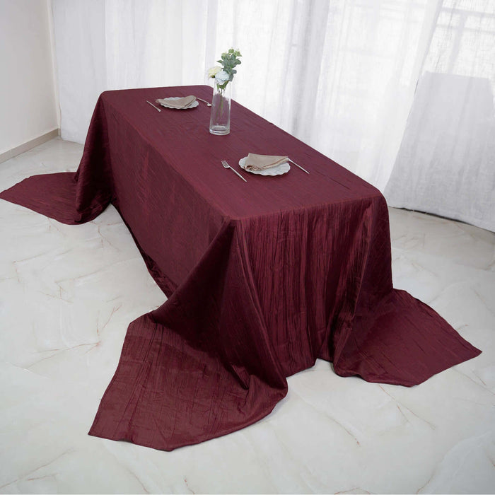 Elegant burgundy tablecloth draped over a dining table with setting.