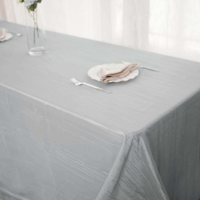 Elegant gray tablecloth draped over a table with plates and napkins set for dining.