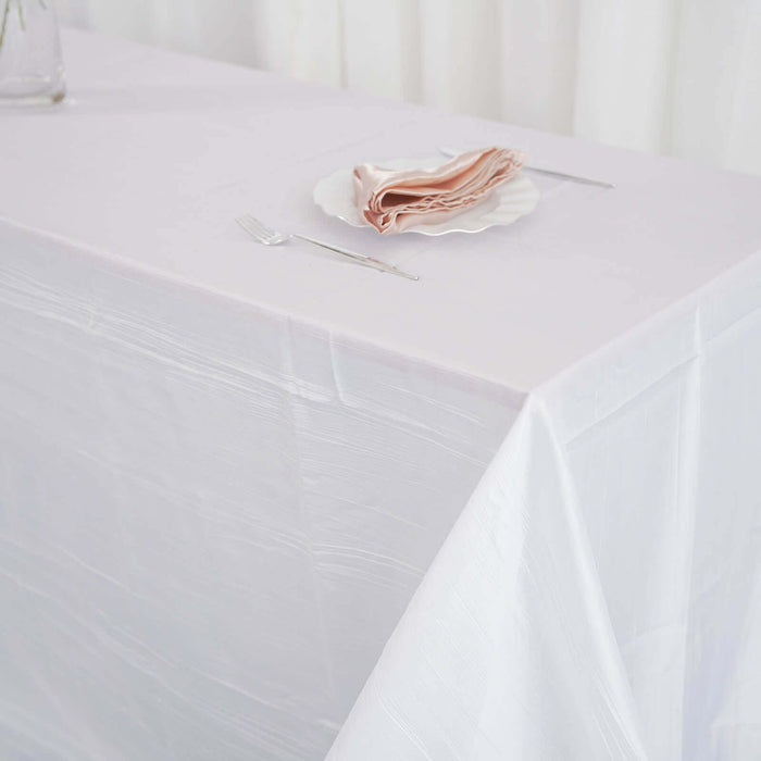 Elegant white table setting with a plate of folded napkins and cutlery.