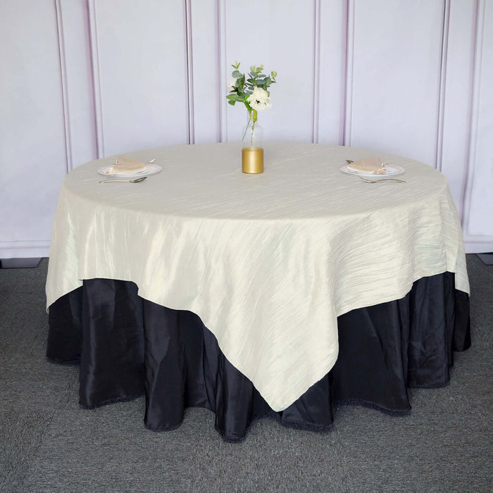 Elegant round table set with a cream tablecloth and black skirt, adorned with flowers.