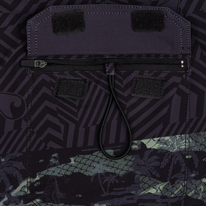 Close-up of the back zip pocket with velcro flap and elastic bungee pull on the Waihana Tropicam W1 board shorts in dark tribal and camo print.