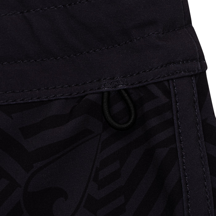 Close-up of the waistband and drawstring cord detail on Waihana Tropicam W1 black board shorts, showing stitching and tonal graphic pattern.